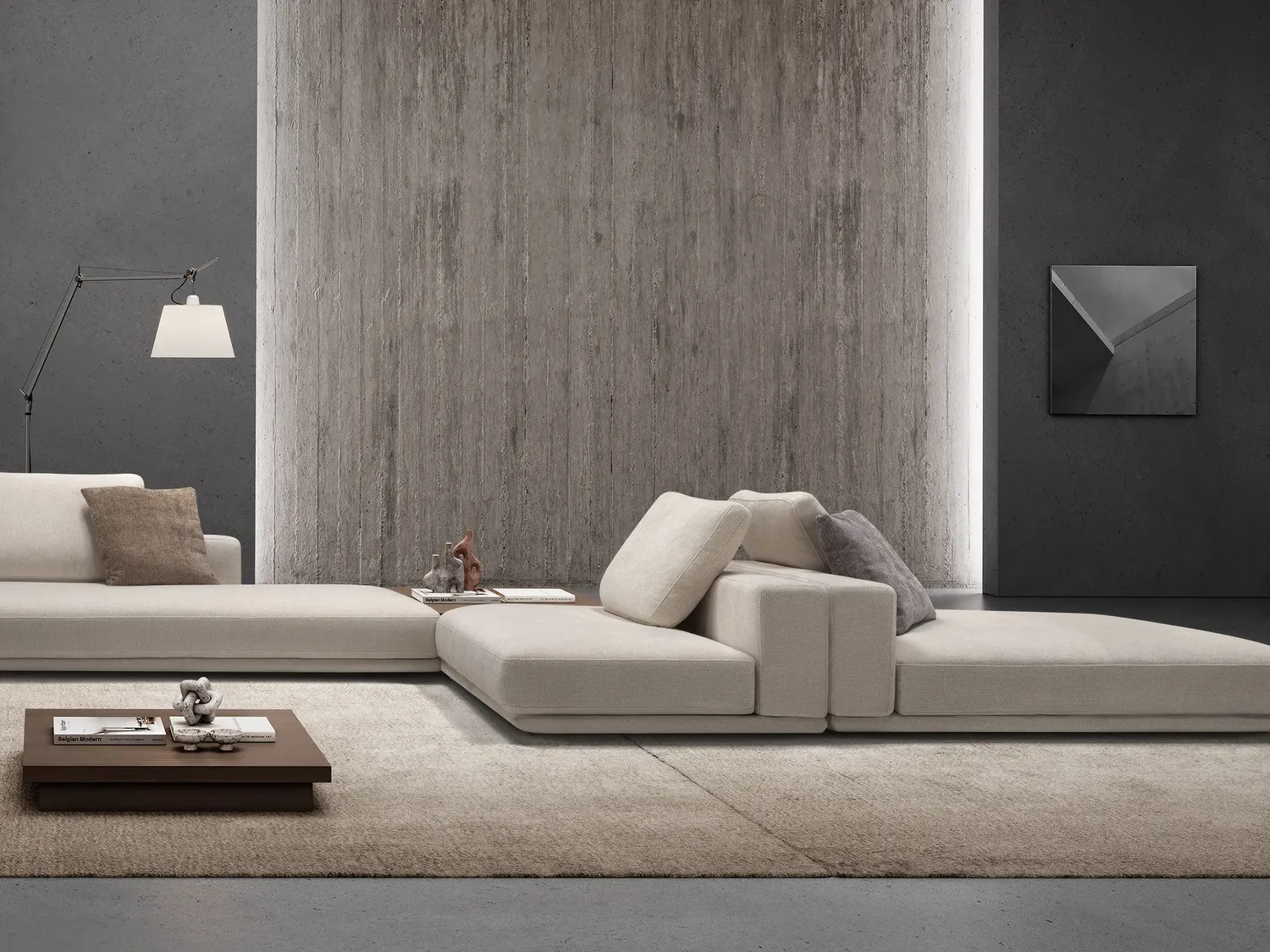 Living con divano basso e parete materica grigia
