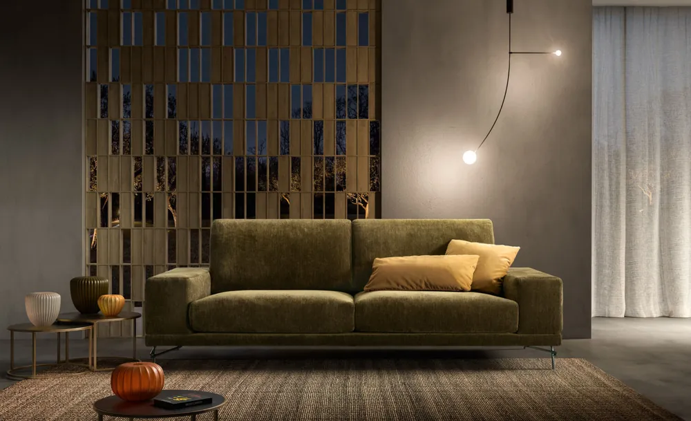 Soggiorno con divano in velluto verde e parete decorativa