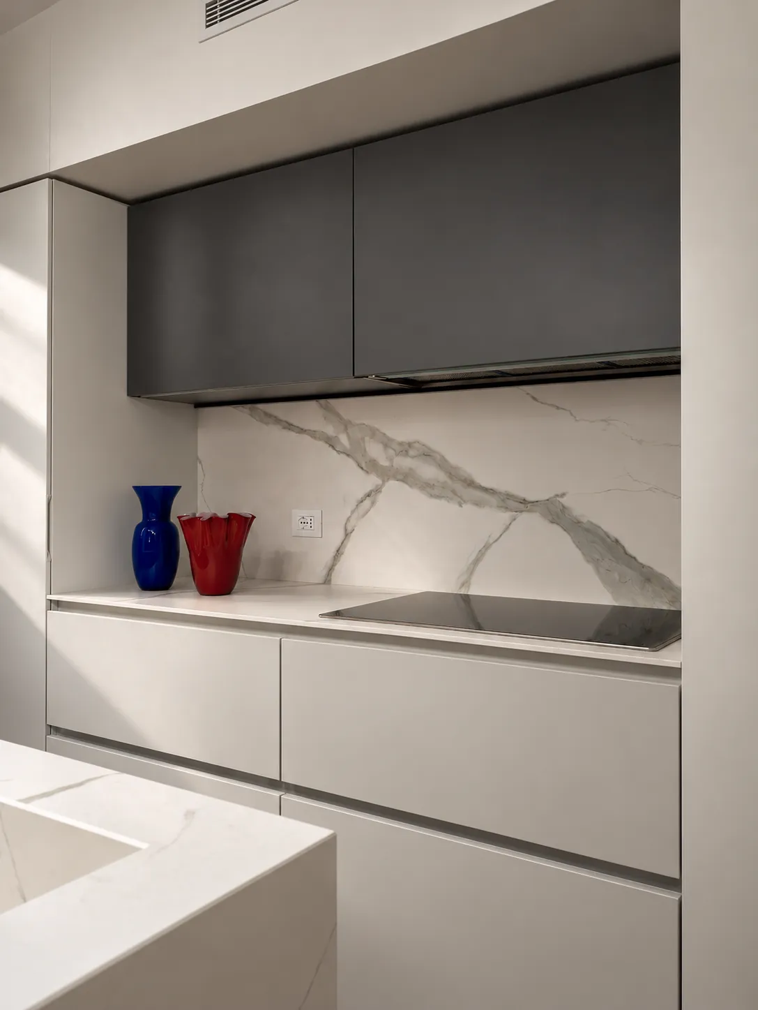 Cucina con top e schienale effetto marmo e vasi in vetro di Murano